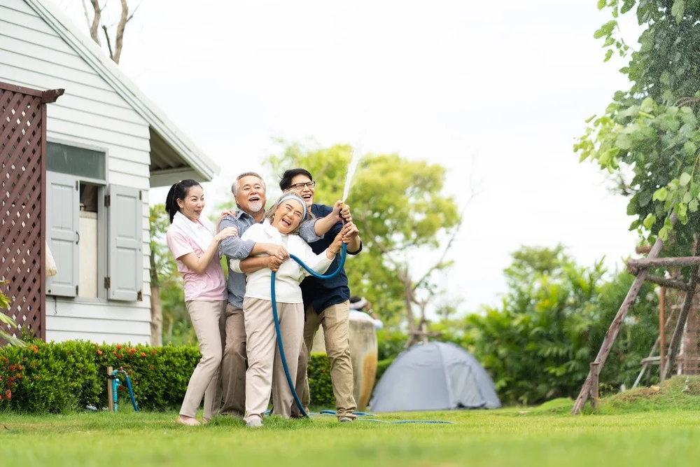 Asian,Family,Happy,Smiling,And,Watering,Green,Cultivated,Plants,With